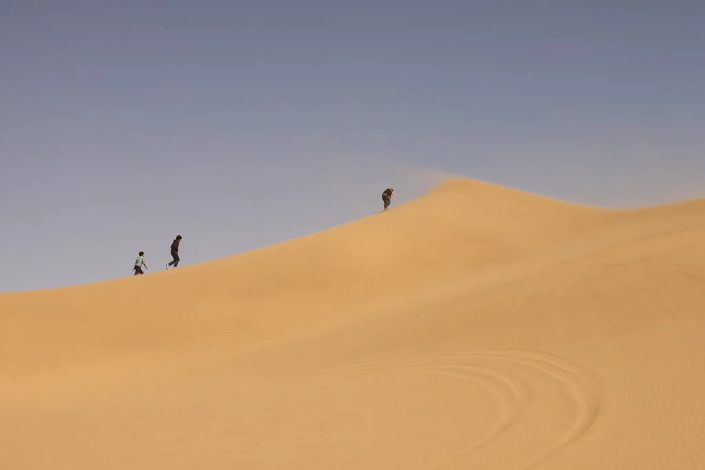 Travellers walking along a golden sand dune in Morocco