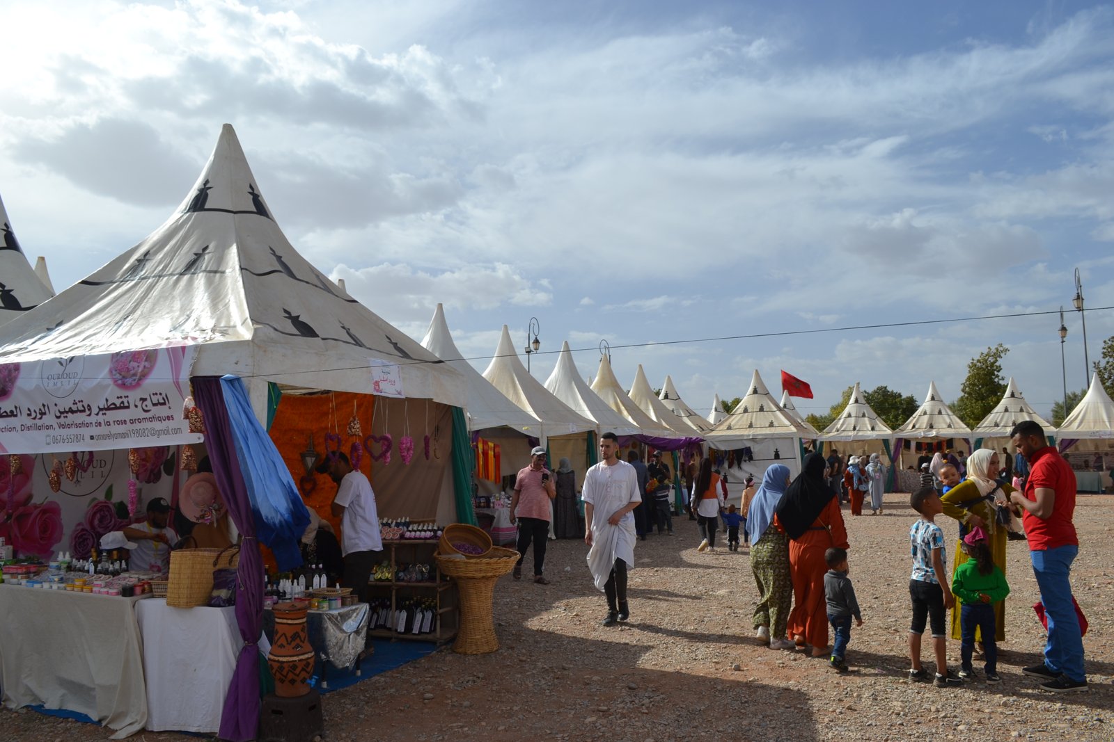 Visitors walk between white tents selling rose products at a fair in Kelaat M’Gouna.