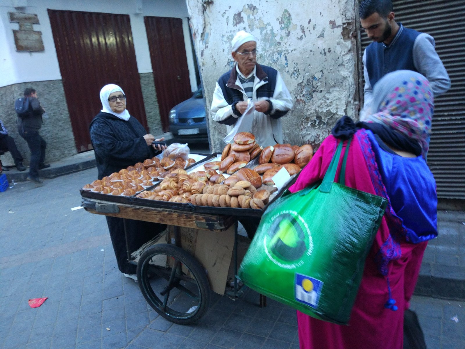 Bread and bakery vendor at a street cart with customers.