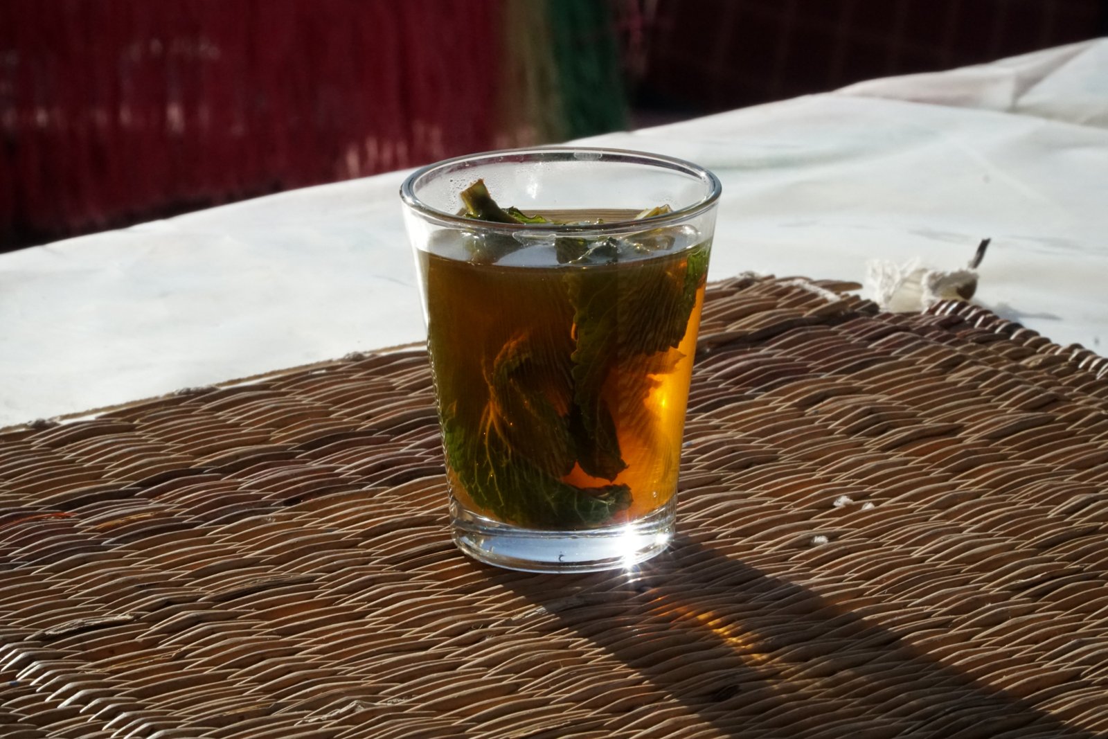 Glass of mint tea on a woven mat.