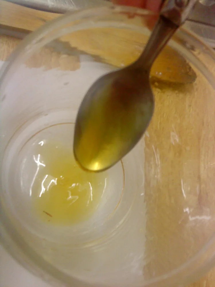 Golden honey on a spoon above a jar