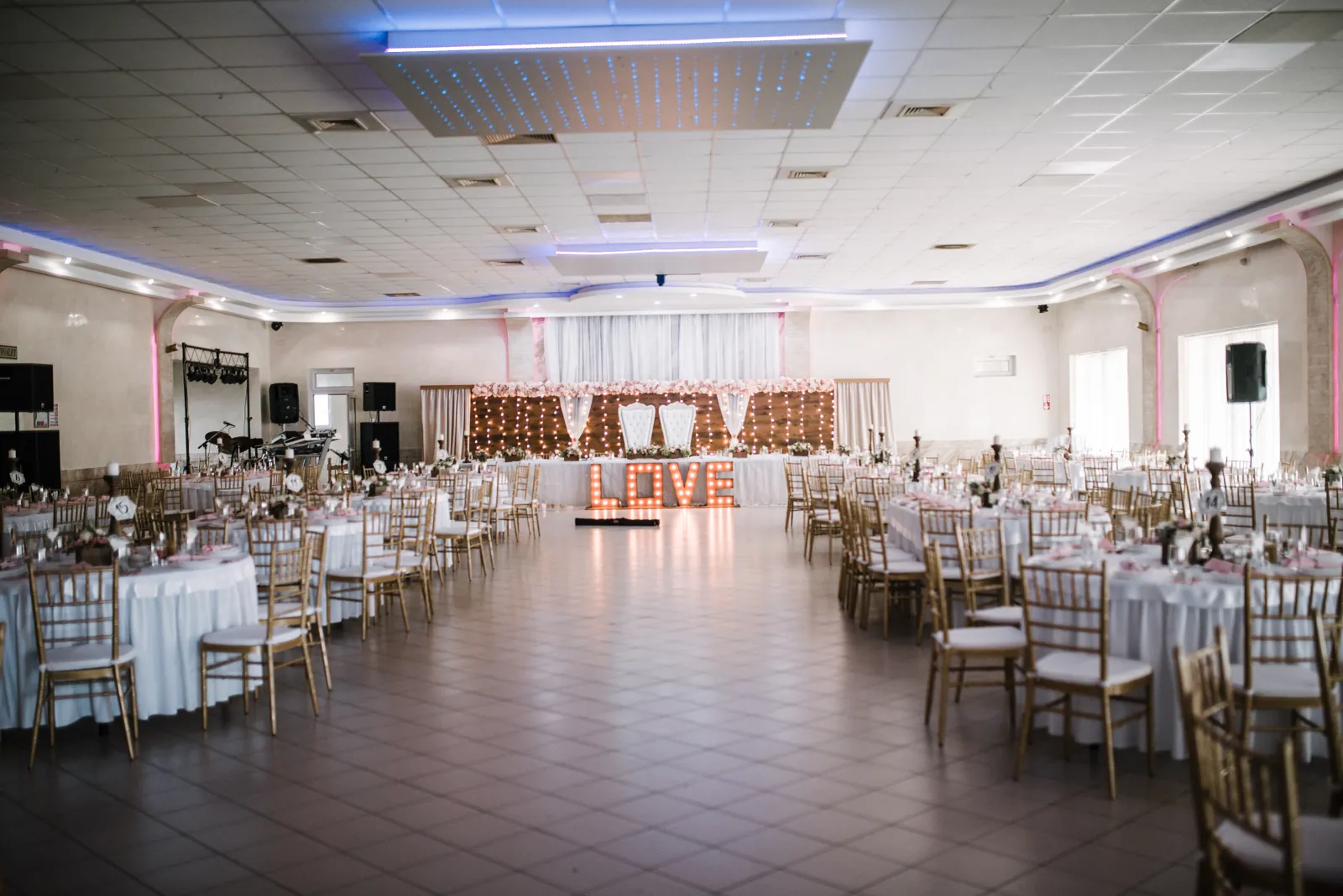 Wedding reception hall with a decorated stage, table settings and flowers